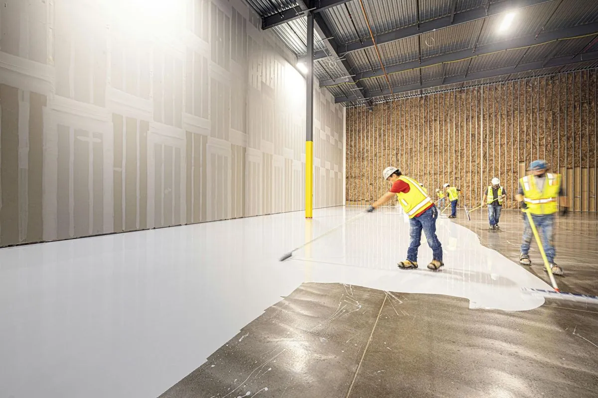 Crew applying epoxy across a warehouse floor