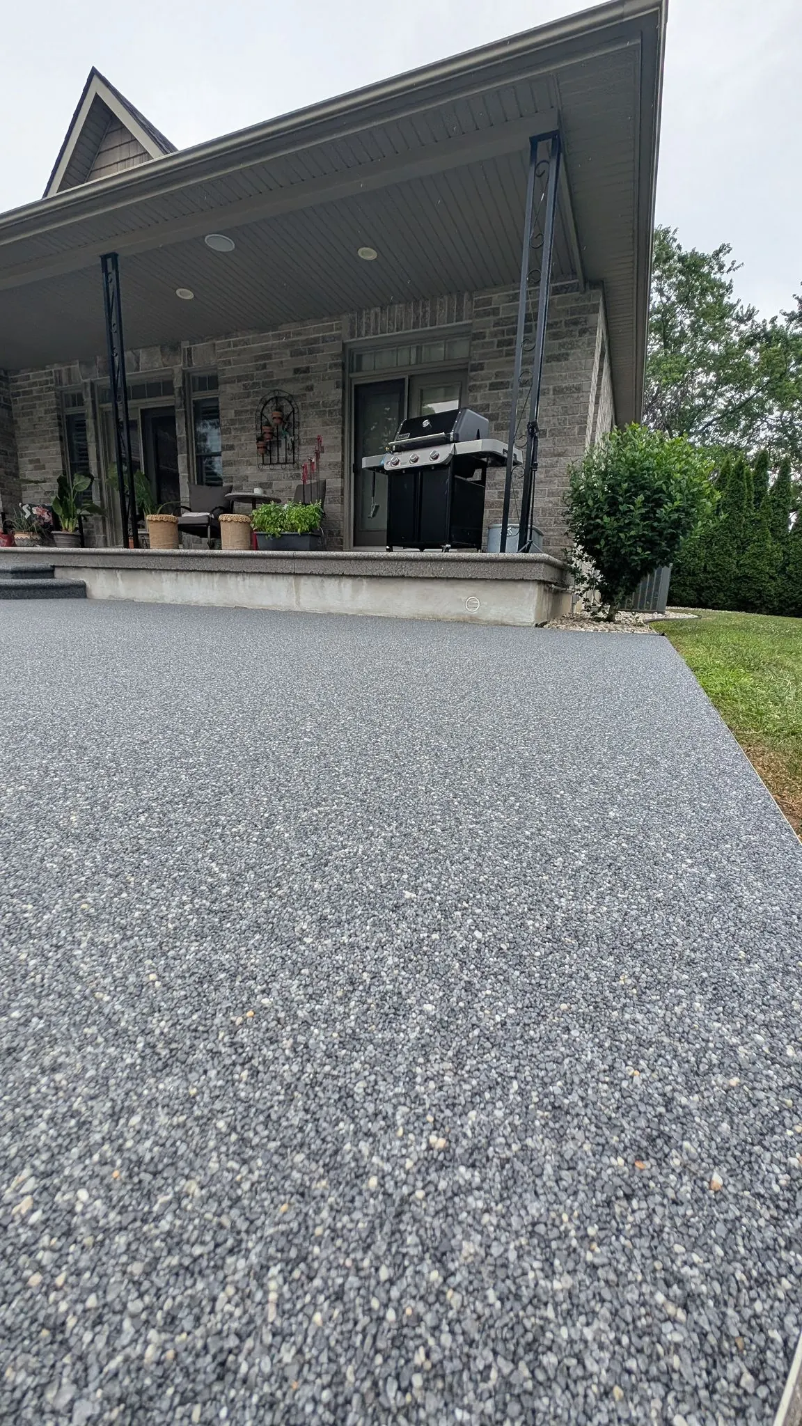 Resin-bound stone patio beside a covered porch